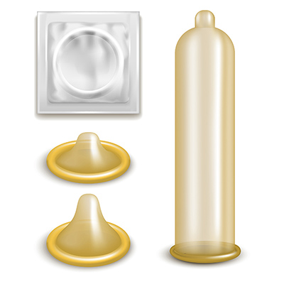 An unrolled external condom next to two rolled up external condoms and a condom wrapper.