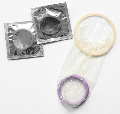 An internal condom with an inner ring and an outer ring next to two condom wrappers.