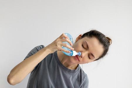 Personne utilisant une bouteille de rinçage nasal souple en plastique