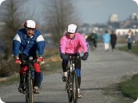 Un homme et une femme portant chacun un casque et faisant de la bicyclette sur une piste cyclable.