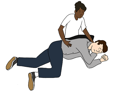 A person helping another person into recovery position (lying down on their left side with right knee bent, left arm extended, and right hand supporting their head).