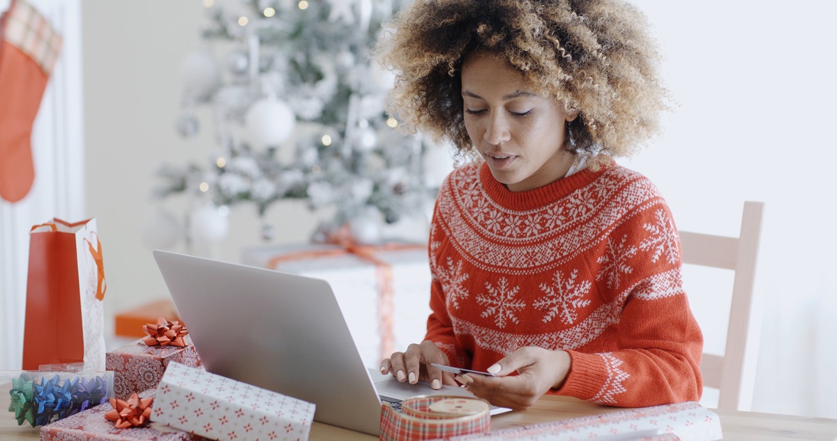 A person in a red sweater using a computer Description automatically generated