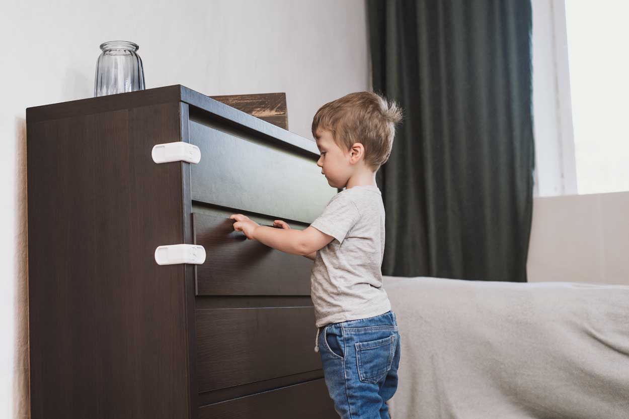 Image 2. Un enfant ne peut pas ouvrir un ensemble de tiroirs à cause des verrous de sécurité.