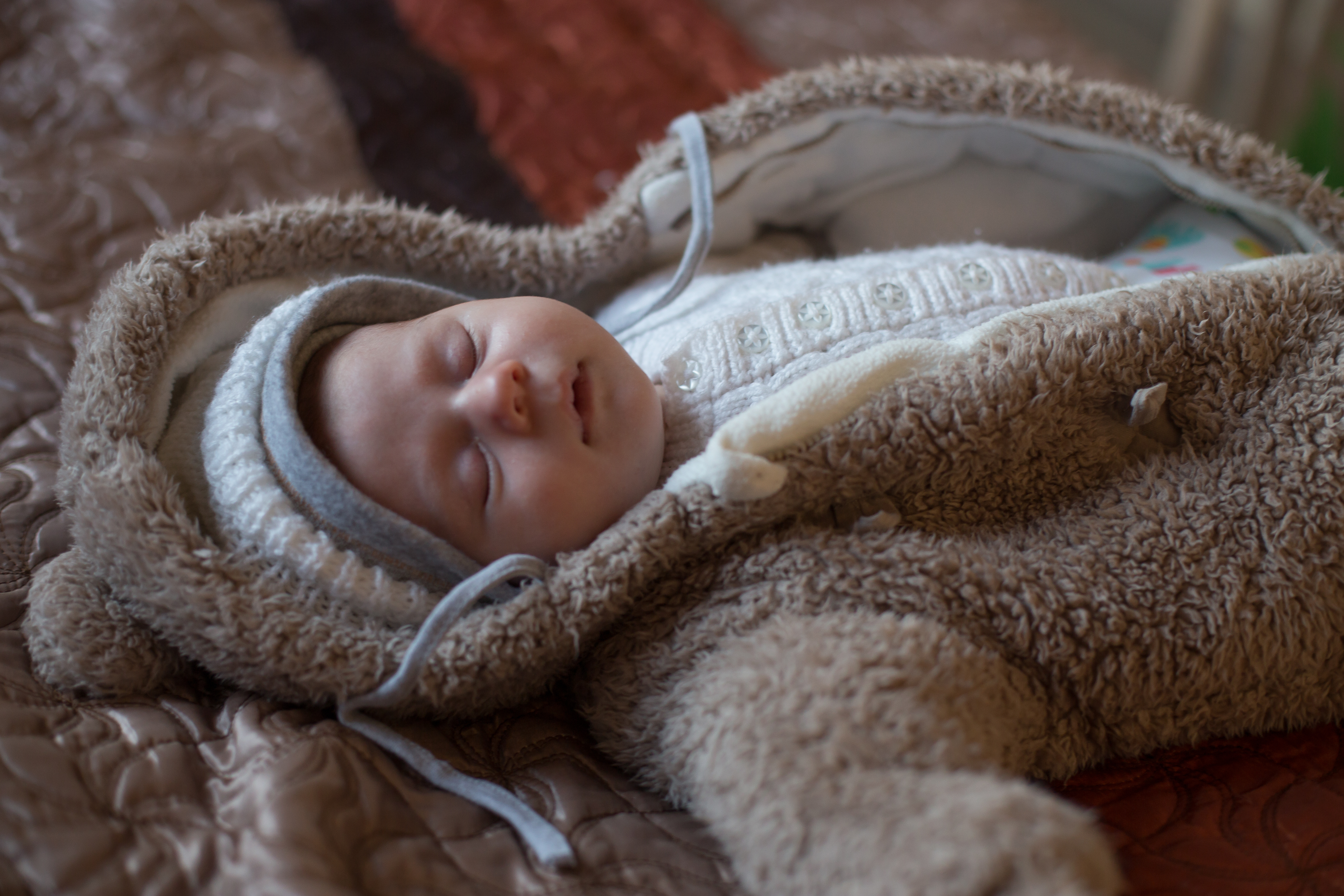 A baby asleep on their back wearing outerwear.