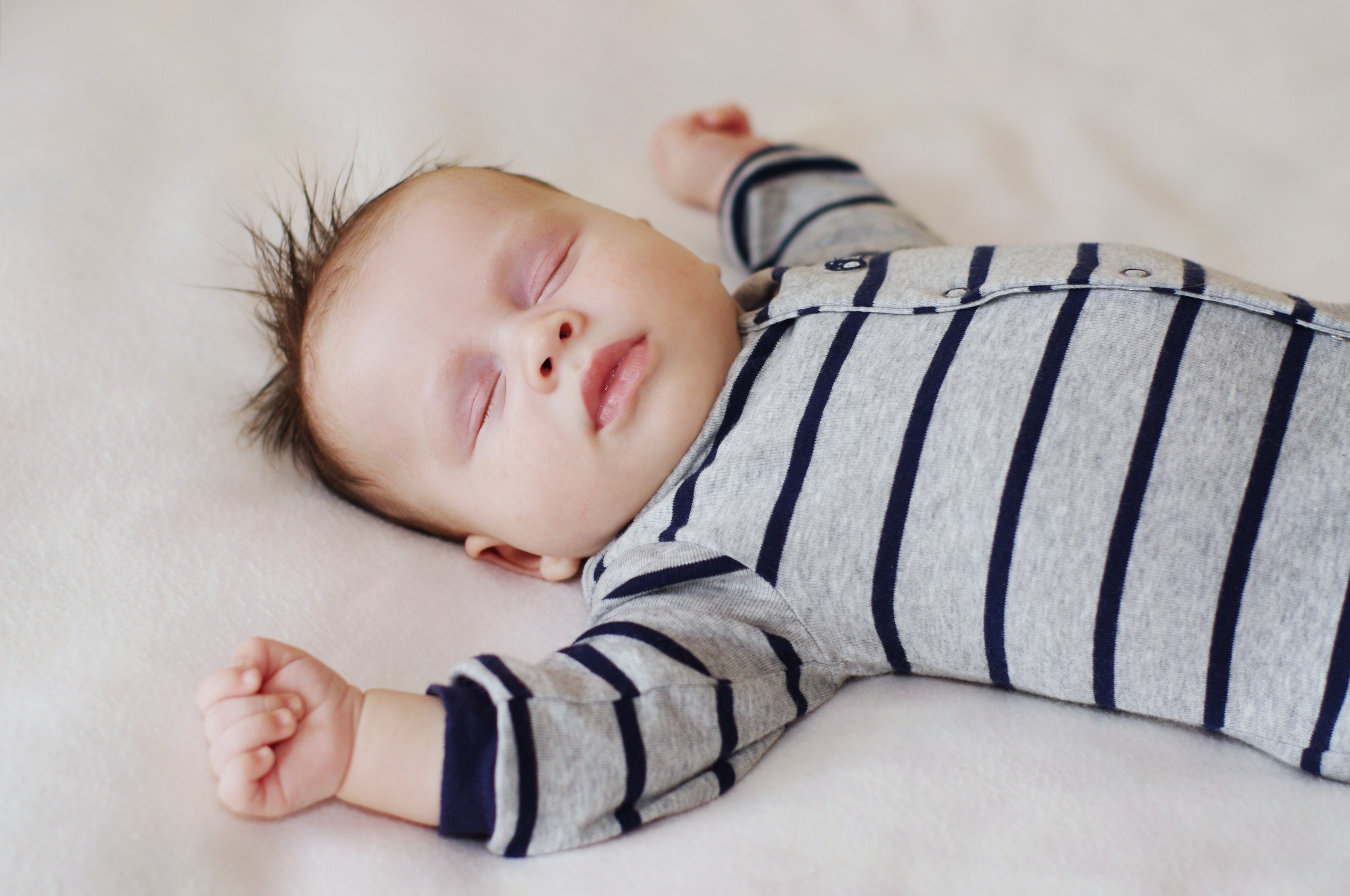 A baby asleep on their back with fully visible face.